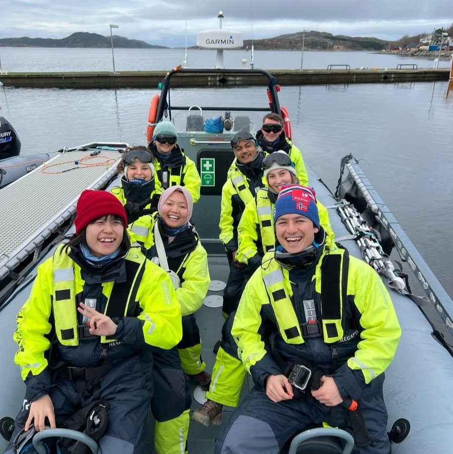 Students in bright yellow jackets is assembled on a boat